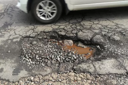 Wet hole and cracked on broken street in urban area