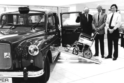 black and white photo of John and Billy Paton standing next to the first wheelchair-accessible FX4 Fairway in the late 1980s