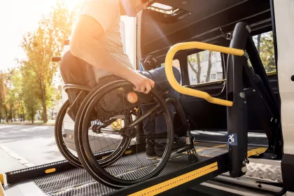 A man in a wheelchair on a lift of a vehicle for people with disabilities.