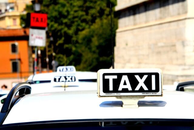 Taxi rank on a street in Rome, Italy with 3 taxis waiting in a queue.
