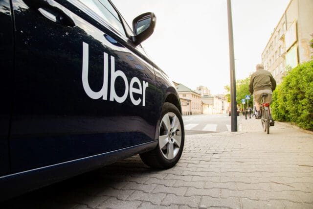 A black Uber taxi parked on a roadside
