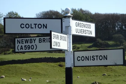 Destination sign post in the Lake District pointing to Colton, Greenwood Ulverston, Newby Bridge, Spark Bridge Lowick, and Coniston.