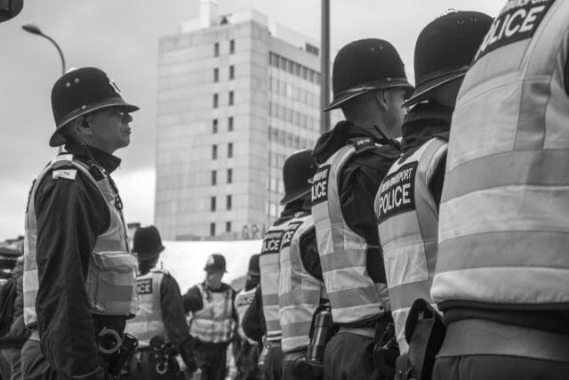 black and white photo of British transport police wearing helmets and high vis jackets