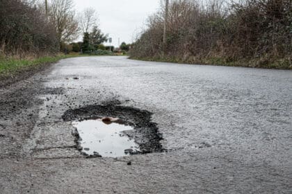 Deep road pothole filled with rainwater on British rural road