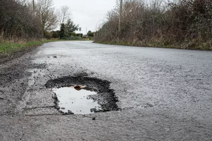 Deep road pothole filled with rainwater on British rural road