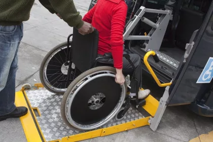 woman in wheelchair using ramp to get into a wheelchair accessible black taxi