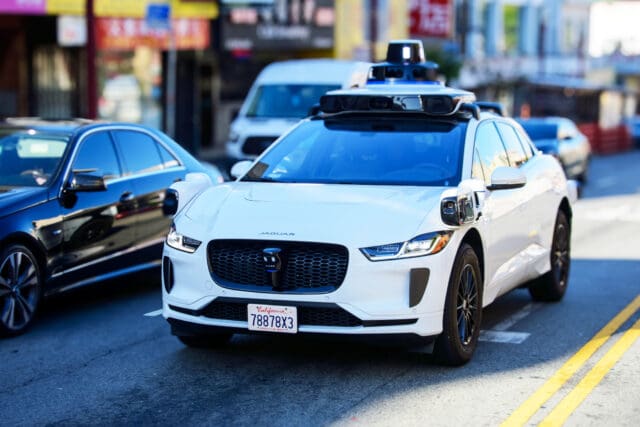 Front side view of Waymo Jaguar driverless car on urban street.