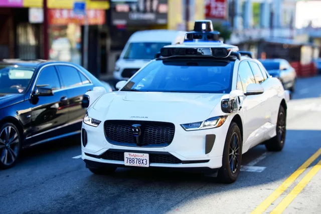 Front side view of Waymo Jaguar driverless car on urban street.