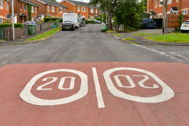 Road markings showing 20 mph speed limited painted on the street at the entrance to a housing estate.