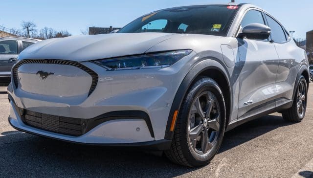 Electric Ford Mustang sedan at a dealership on a sunny day