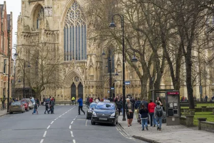 York Taxi rank. Street view from Dumcombe Place showing York Minster at the back and pedestrians walking by. The cathedral dates back from 1291.