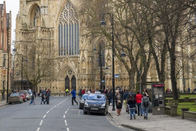 York Taxi rank. Street view from Dumcombe Place showing York Minster at the back and pedestrians walking by. The cathedral dates back from 1291.