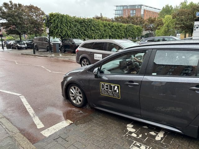 Delta taxi and uber crossing paths at the Albert Dock in Liverpool. Taxi licensing fees in Liverpool are set to rise for the first time in 15 years.
