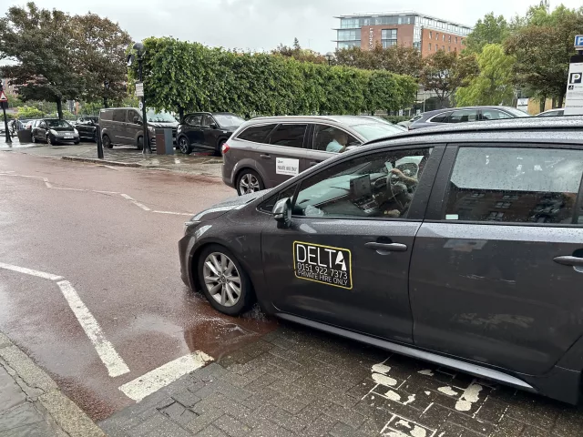 Delta taxi and uber crossing paths at the Albert Dock in Liverpool. Taxi licensing fees in Liverpool are set to rise for the first time in 15 years.
