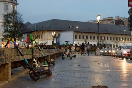 e scooters parked on the pavement next to a busy road