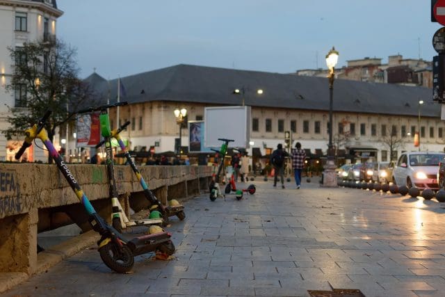 e scooters parked on the pavement next to a busy road