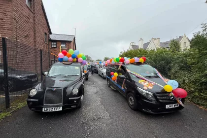 Two black cabs decorated with balloons for the Liverpool Taxi Outing 2025.