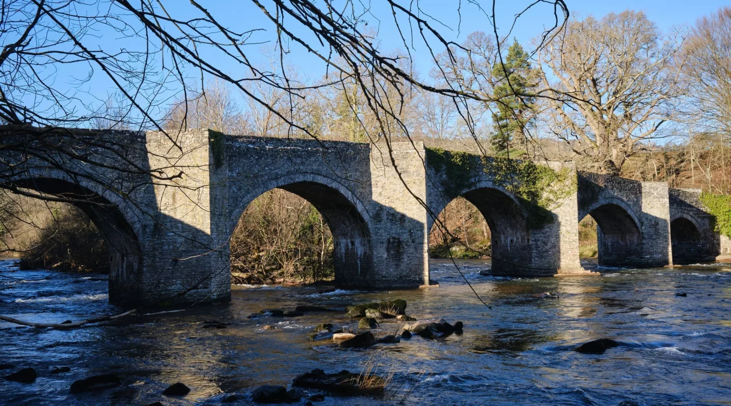 arched stone bridge over a river, photographed on a sunny day in winter