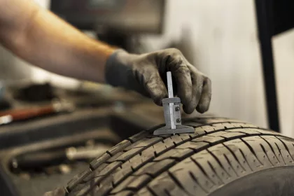 Mechanic is using a caliper to check the tread depth of a tire to determine if it needs replacing.