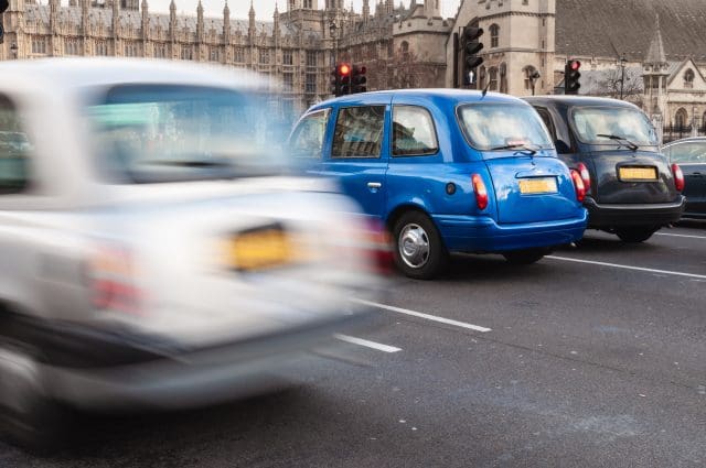 London, UK typical London taxis waiting by the traffic light in front of Westminster