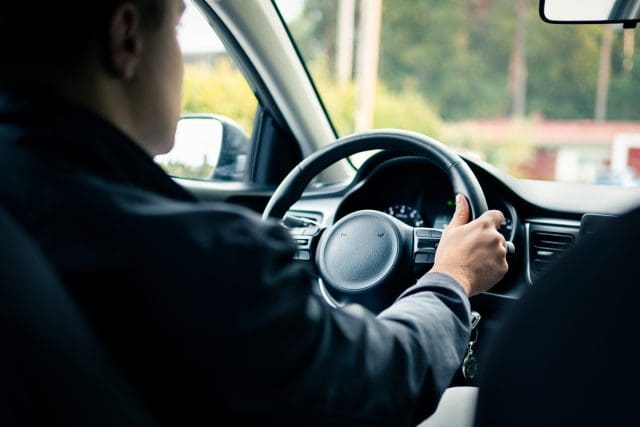 Driver in rideshare car or taxi. Behind view.