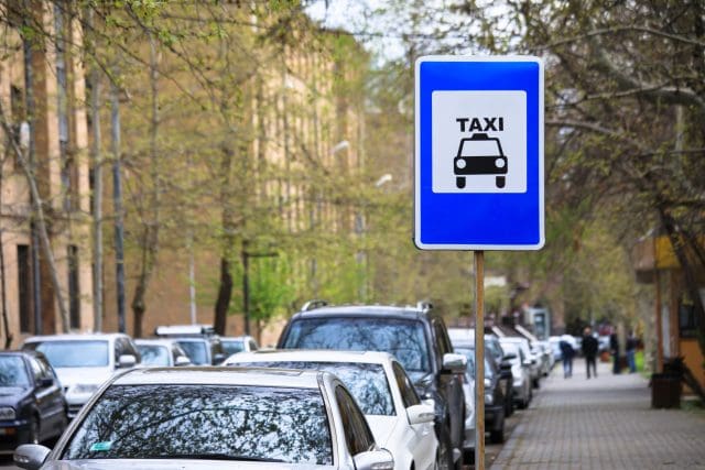 Sign "Taxi" with taxi car behind