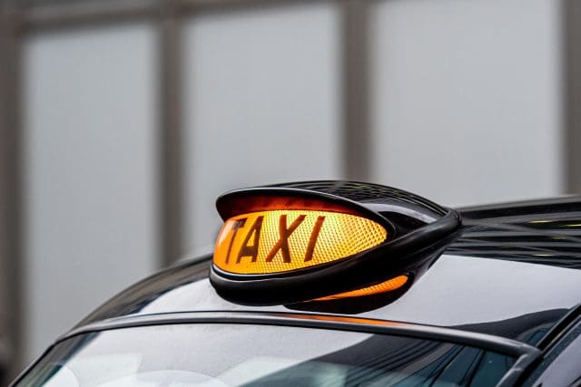 A british london black taxi cab sign with defocused background