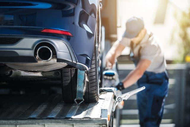 Towing Truck Delivery. Shipping Modern Vehicle to Car Dealership