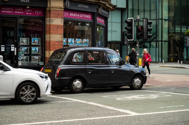 Public hire black cab taxi waiting at traffic light