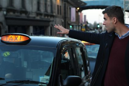 Passenger hailing a British black cab taxi