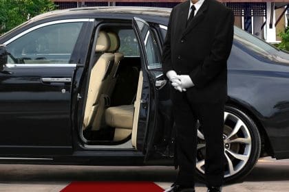 chauffeur driver standing next to opened car door with red carpet