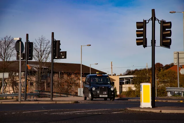 Black cab taxi in Glasgow crossing the road and traffic lights