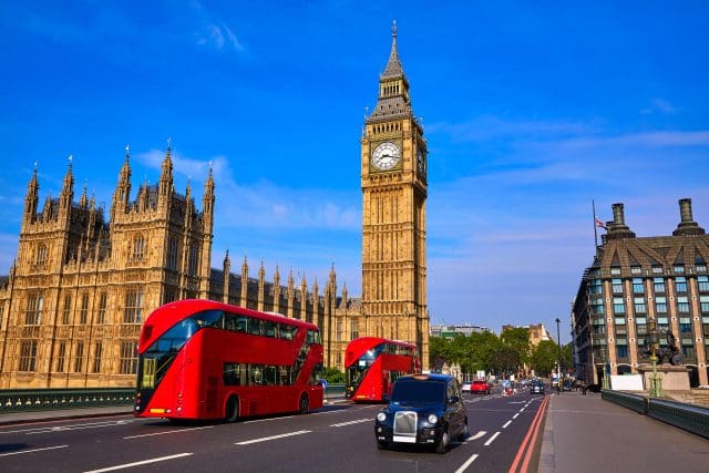 Black cab taxi driving down road with Big Ben Clock Tower in view in London, England
