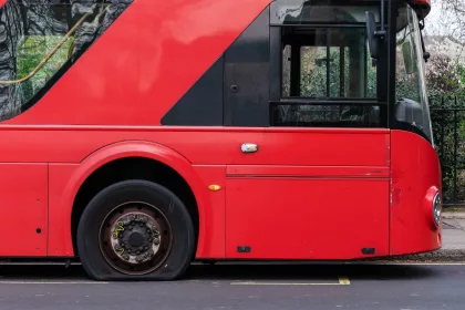 Flat tire on a red double decker bus.