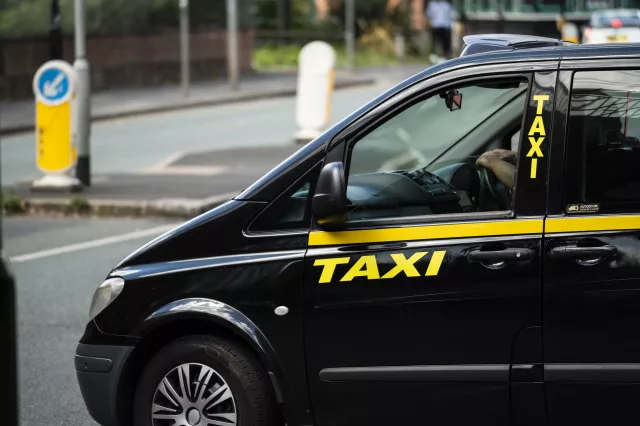 Black cab taxi driving down main road
