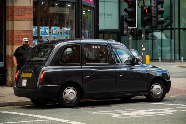 black cab taxi waiting at red traffic light