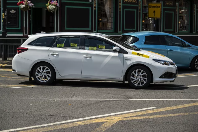 private hire vehicle taxi driving on city street