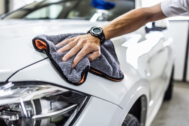 A man cleaning car with microfiber cloth, car detailing (or valeting) concept