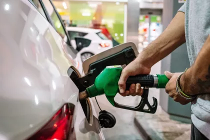 Person putting fuel dispenser in tank while refueling vehicle at self service petrol station.