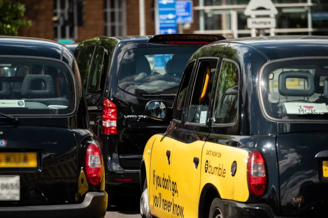 Black hackney carriage taxis driving through city