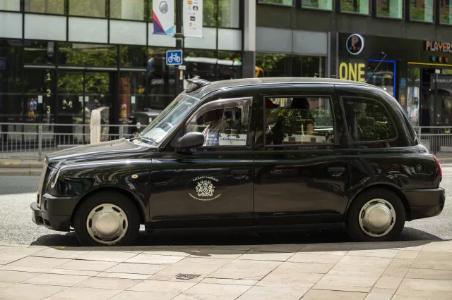 Side view of black cab taxi parked stationary in taxi rank