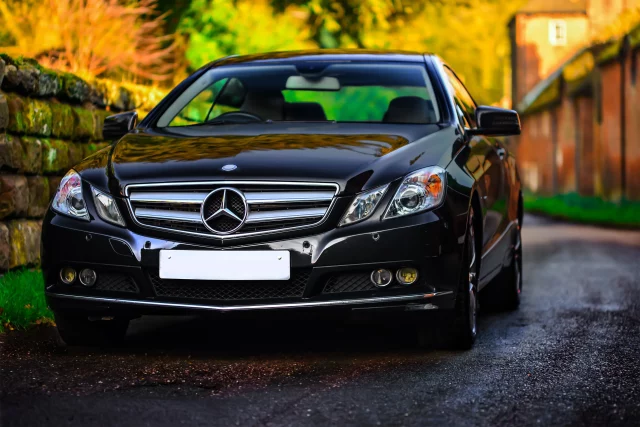 black mercedes e-class driving down residential street