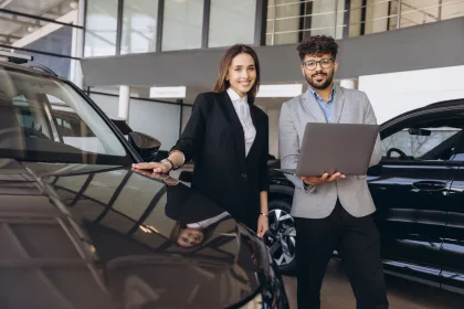 Salesman showing new car to customer in dealership