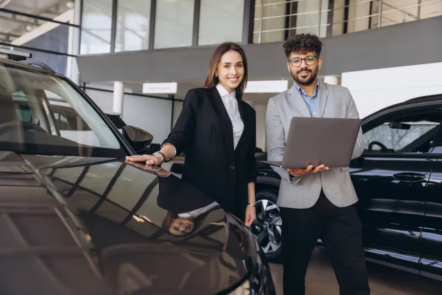 Salesman showing new car to customer in dealership