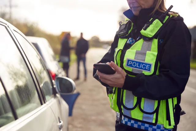 Female Traffic Police Officer Recording Details Of uninsured vehicle