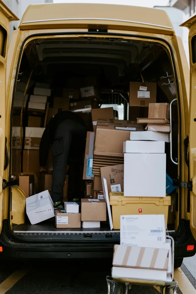 back of a van, doors open with a pile of cardboard boxes inside