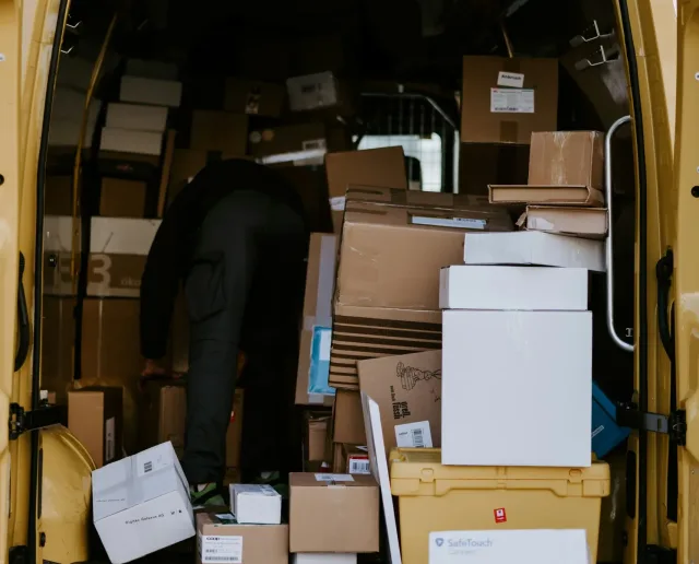 back of a van, doors open with a pile of cardboard boxes inside