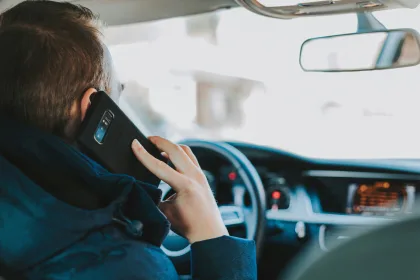 driver holding a mobile phone to his ear while driving