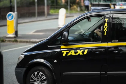 side view of hackney carriage with yellow 'TAXI' wording below the wing mirror and on the side of the window