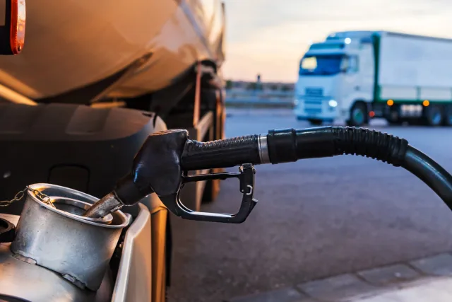 Fuel nozzle from a petrol station filling a truck tank.